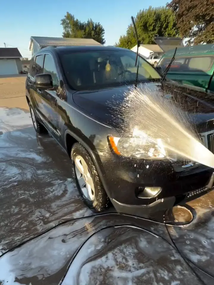 Prelavado con espuma enjuagado de un Jeep negro en una cochera