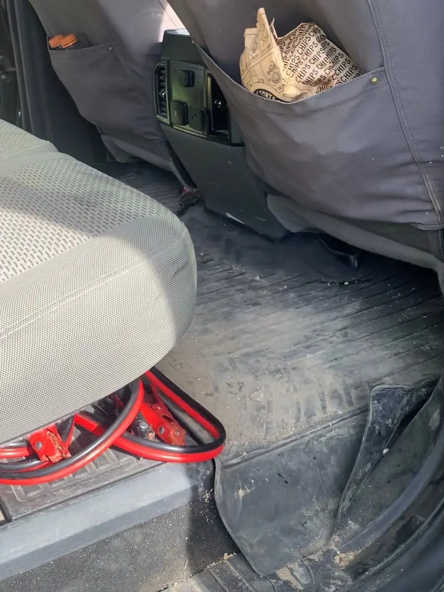 Área del asiento trasero de una camioneta con lodo en el tapete antes de la limpieza