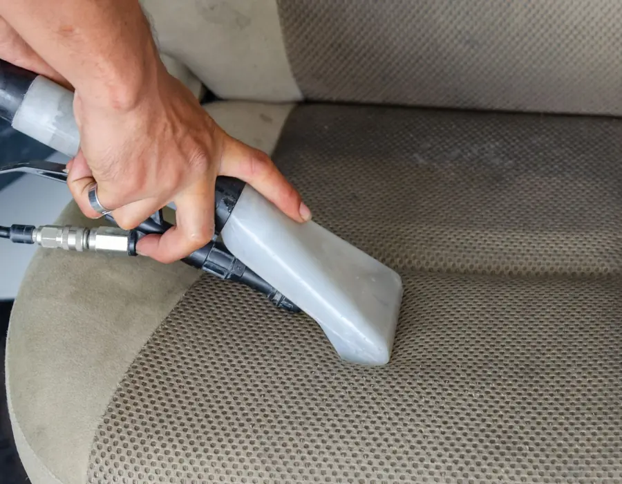 Upholstery extractor cleaning a cloth car seat