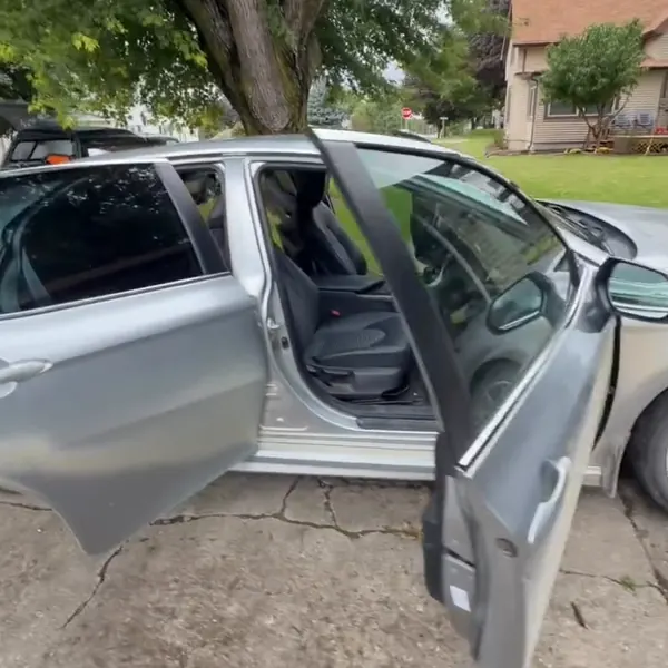 Auto plateado con las puertas abiertas en la cochera de un cliente durante un detallado a domicilio